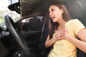 Wall Mural - Young woman suffering from heart attack in car