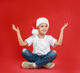 Sticker - Cute little child wearing Santa hat on red background. Christmas holiday