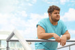 Young overweight man leaning on railing outdoors