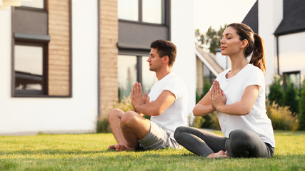 Canvas Print - Sporty couple practicing morning yoga at backyard. Healthy lifestyle