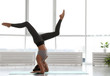 Young woman practicing headstand with splits in yoga studio