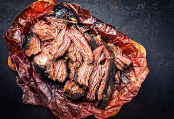 Wall Mural - Traditional barbecue wagyu pulled beef in peach paper as closeup on a rustic board