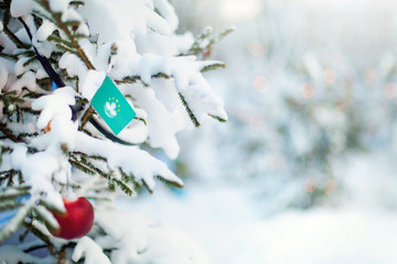 Christmas Macau. Xmas tree covered with snow, decorations and Macau flag. Snowy forest background in winter. Christmas greeting card.