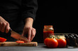 © Anton - Chef cooks pizza, slices fresh tomatoes, on the background with ingredients. Recipe book, menu, home cooking. Horizontal frame.