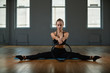© Georgii - A young, beautiful, athletic girl does exercises with a Pilates ring in the gym. Sports Slavic girl in a black suit. Copy space, gray background, sport banner for advertising.