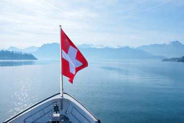 Wall Mural - Swiss flag flying on boat and Rigi mountain view background