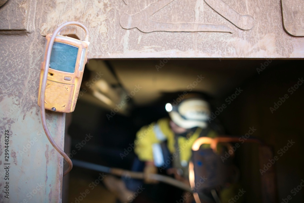 Unfocused, blurry picture of rope access miner working inside the confined space while yellow gas test detector atmosphere is hanging on the entry door frame, construction mine site Perth, Australia   - obrazy, fototapety, plakaty 