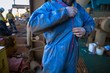 © Kings Access - Male dressing and zipping up blue contaminate disposable protective clothing uniform prior working on construction site