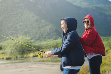 Wall Mural - Happy Asian couple fishing together with nature background, lifestyle concept.