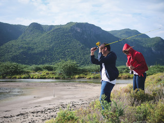 Wall Mural - Happy Asian couple fishing together with nature background, lifestyle concept.