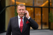 © Ranta Images - Handsome senior businessman with mustache using phone in the city