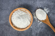Pastry flour on wooden bowl on gray background, top view - homemade flour on spoon for cooking ingredients on kitchen table