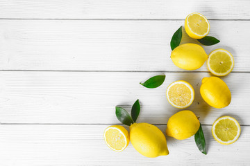 Fresh juicy lemons on white rustic table. Top view lemon background and leaves.