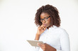 © Mangostar - Serious focused manager watching presentation on tablet. Young African American female professional standing isolated over white background. Digital device using concept