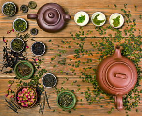 Wall Mural - Chinese tea on a wooden background. Tieguanyin and other chinese tea in the glass cups, two clay teapots. Top view.