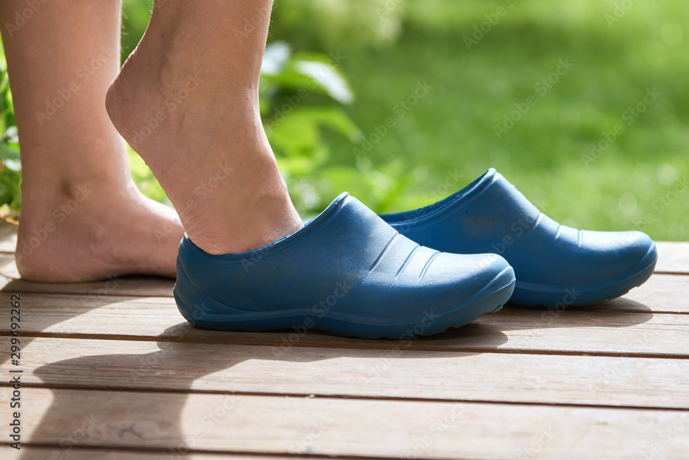 Young Barefoot girl puts rubber boots on standing on the porch of a ...