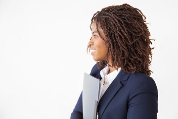 Wall Mural - Happy cheerful office employee holding folder with documents, looking at copy space. Young African American business woman posing isolated over white background. Advertising concept