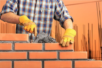 Bricklayer industrial worker installing brick masonry