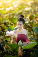 Wall Mural - Asian woman collecting lotus flowers and she wear Traditional Thai dresses, Thailand