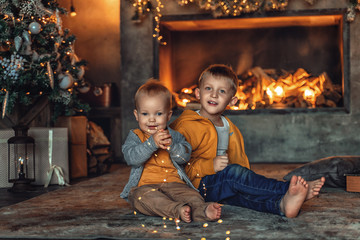 Two boys, two brothers play under the Christmas tree in the New Year.