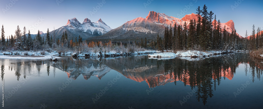 Obraz na płótnie Almost nearly perfect reflection of the Three Sisters Peaks in the Bow River. Near Canmore, Alberta Canada. Winter season is coming. Bear country. Beautiful landscape background concept. w salonie