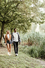 Happy Young Couple Holding Hands While Walking In Autumn Park