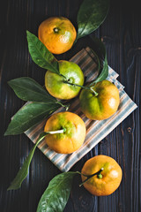 Wall Mural - Tangerines with leaves on an old fashioned country table. Selective focus. Vertical.