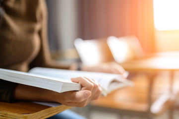 Students read books at the university classroom desk.