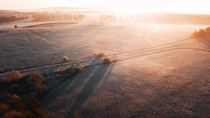 Wall Mural - Aerial foggy and frozen morning countryside nature with golden autumn sunrise light and long shadows. Aerial drone view of German landscape with mist in winter times. Harz Mountains