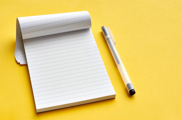Top view of blank open notebook page with lines and transparent minimalistic fineliner pen on yellow background with copy space. For use as mock up.    