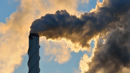 Factory pipe close-up with a lot of smoke against blue sky