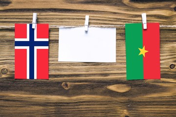 Wall Mural - Hanging flags of Bouvet Islands and Burkina Faso attached to rope with clothes pins with copy space on white note paper on wooden background.Diplomatic relations between countries.