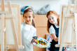 © LIGHTFIELD STUDIOS - selective focus of adorable kids standing near easels