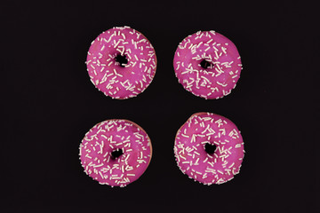 Wall Mural - For donuts with bright pink chocolate glazing and white sugar sprinkles on black background