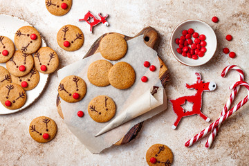 Wall Mural - Cooking Christmas gingerbread. Decorating red nosed reindeer cookies with chocolate buttons and melted chocolate. Festive homemade decorated sweets