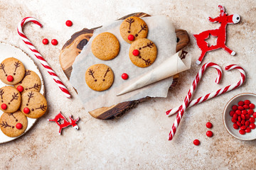 Wall Mural - Cooking Christmas gingerbread. Decorating red nosed reindeer cookies with chocolate buttons and melted chocolate. Festive homemade decorated sweets