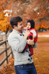 Wall Mural - Happy smiling Caucasian father dad with cute adorable baby girl in ladybug costume. Family in autumn fall park outdoor with yellow orange leaves trees. Halloween seasonal concept.