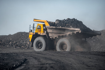 Open pit mine industry. Big yellow mining truck for coal moving on road career