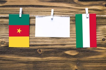 Wall Mural - Hanging flags of Cameroon and Hungary attached to rope with clothes pins with copy space on white note paper on wooden background.Diplomatic relations between countries.