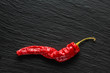Single red dried banana pepper on a dark gray slate with copy space