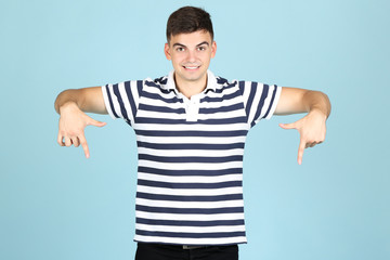 Canvas Print - Young man showing fingers down on blue background