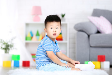 Beautiful boy sitting on carpet at home