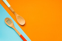 Two Wooden Spoons On A Orange And Blue Background, Top View, Copy Space