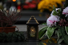 Bouquet Of Flowers In A Vase At The Cemetery, Candles On The Grave