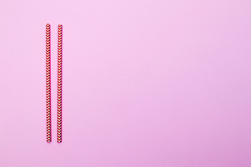 Two red straws for cocktail isolated on red background. Copy space