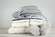 Folded knitted sweaters with fluffy earmuffs and scarf on grey background