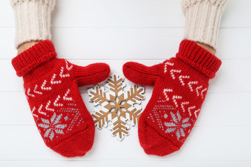 Wall Mural - Hands in knitted mittens with snowflake on white wooden table