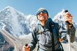 © Soloviova Liudmyla - Portrait of smiling Hiker man on Taboche 6495m and Cholatse 6440m peaks background with trekking poles, UV protecting sunglasses. He enjoying mountain views during Everest Base Camp trekking route.