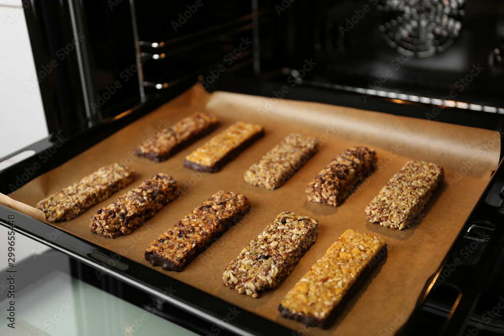 Delicious healthy granola bars on baking sheet in oven - obrazy, fototapety, plakaty 