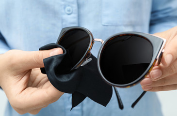 Sticker - Woman wiping sunglasses with microfiber cleaning cloth, closeup